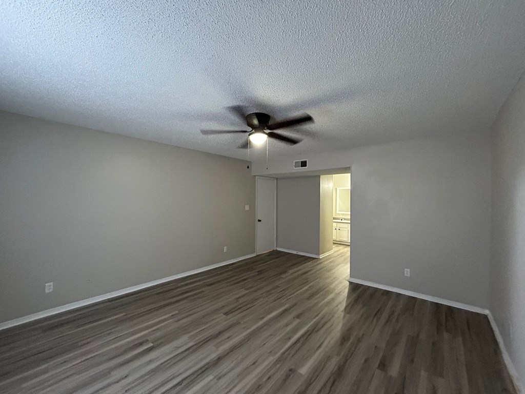 A room with a ceiling fan and wooden flooring.