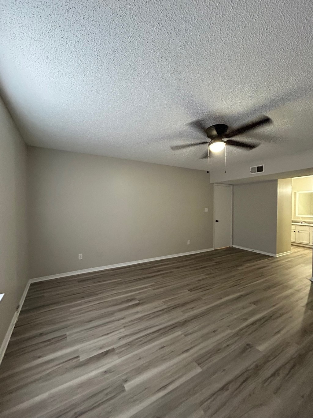 A room with a ceiling fan and wooden flooring.