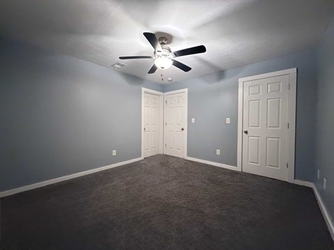 A room with a ceiling fan and two doors.