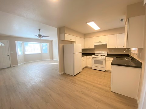 A kitchen with white cabinets and a black countertop.