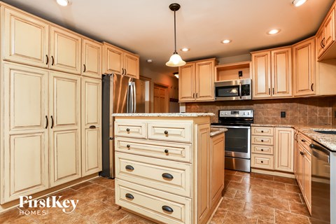 A kitchen with wooden cabinets and a tiled floor.