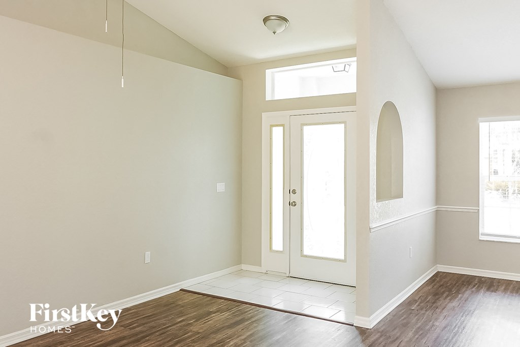 an empty living room with a white door and a window