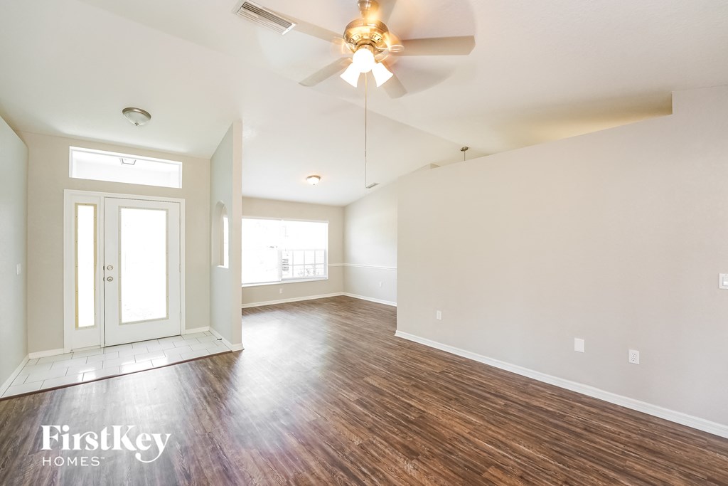 an empty living room with wood flooring and a ceiling fan