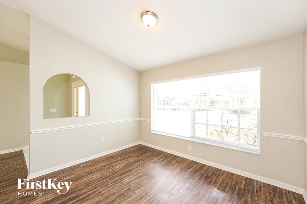an empty living room with a large window and wood flooring