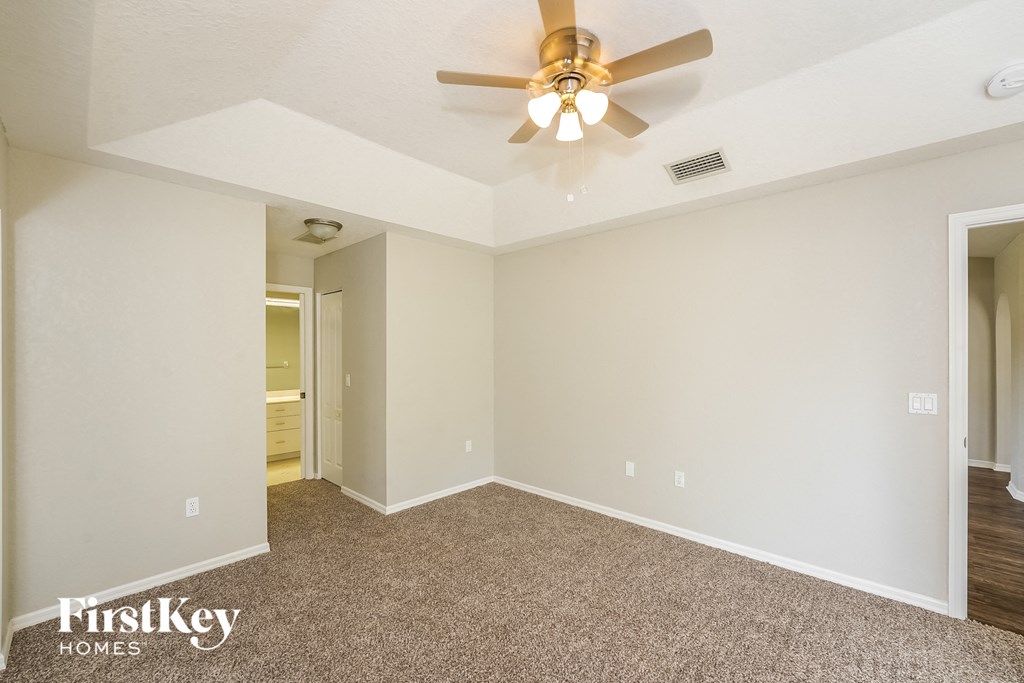 the spacious living room with ceiling fan and carpeting