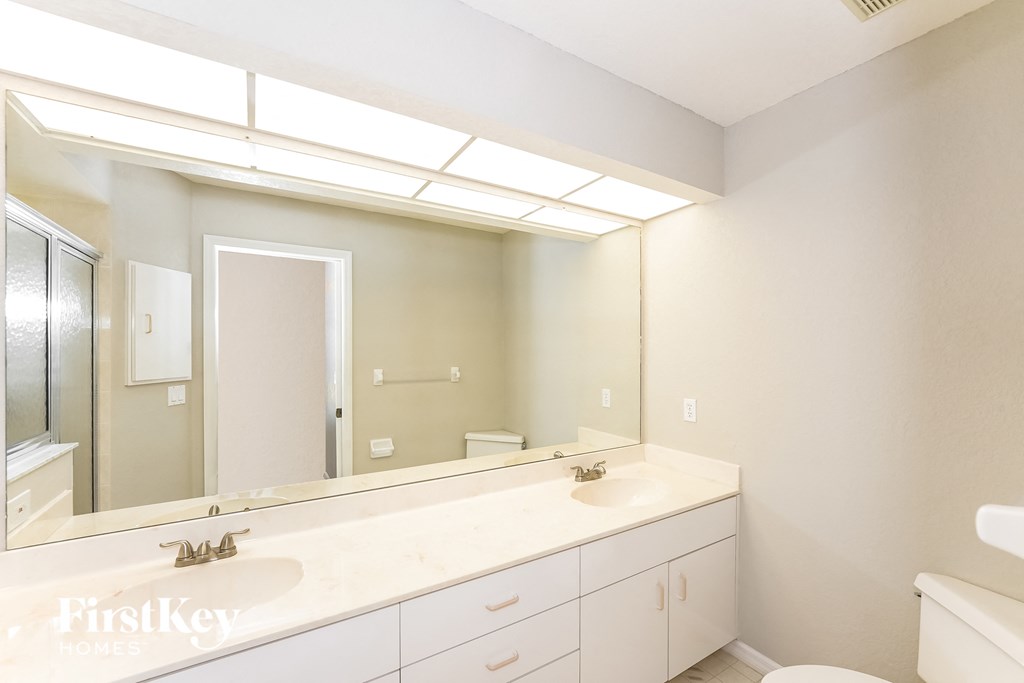a bathroom with a large mirror and a sink and a toilet
