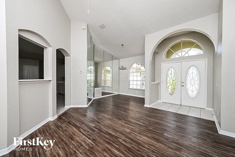 the living room and entryway of a house with white walls and wood floors