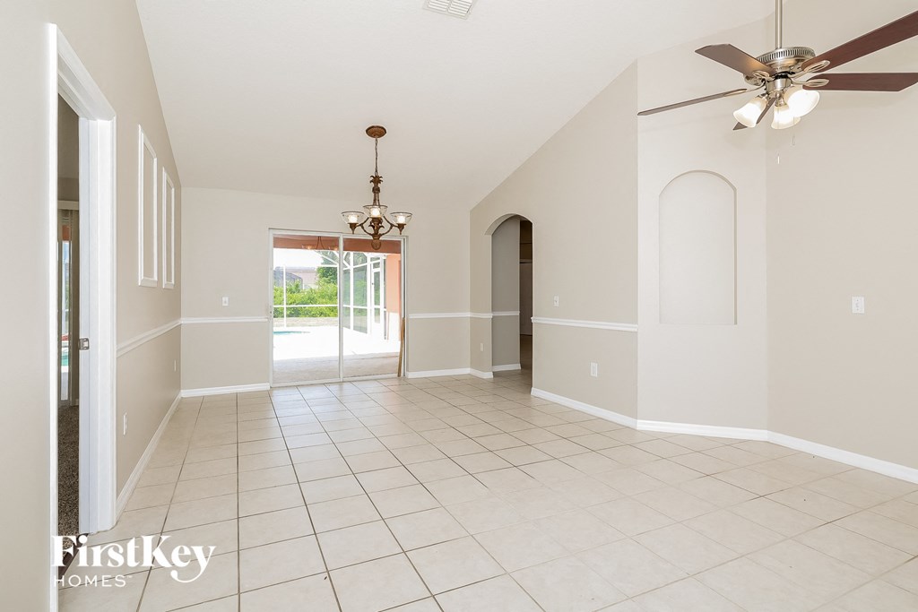 an empty living room with a ceiling fan and tiled floor