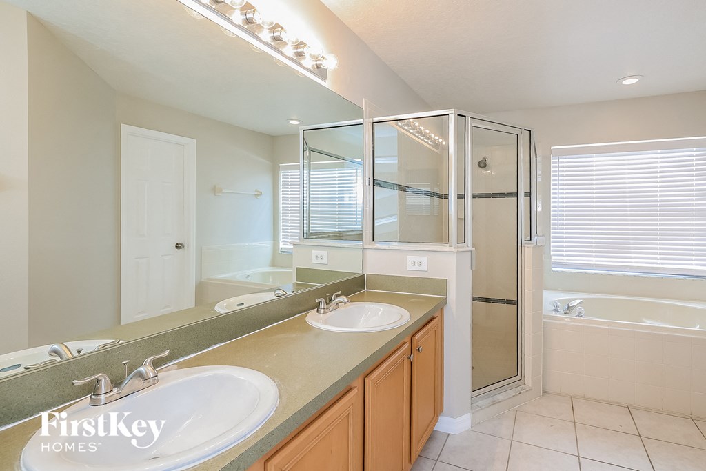 a bathroom with two sinks and a shower and a tub