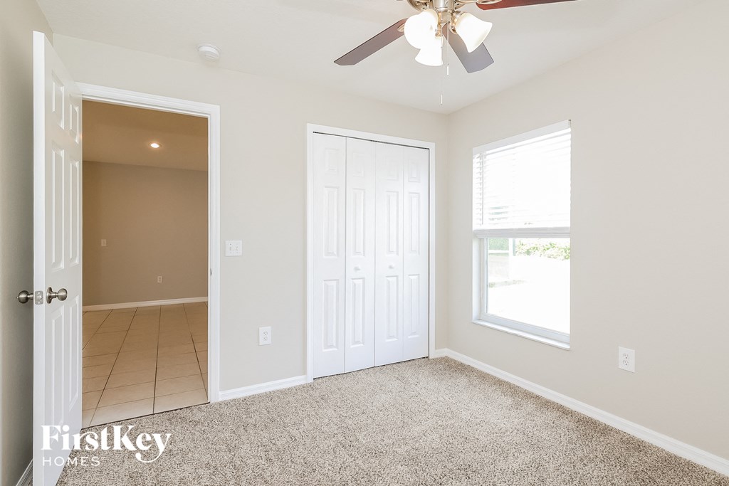 a bedroom with a ceiling fan and a door to a closet