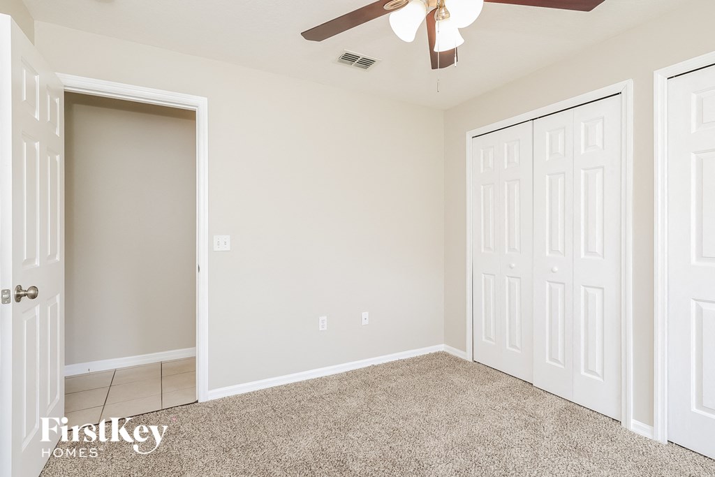 a bedroom with two closets and a ceiling fan