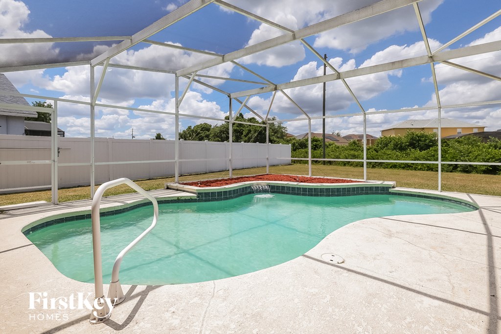 a resort style pool with a white fence and a house in the background