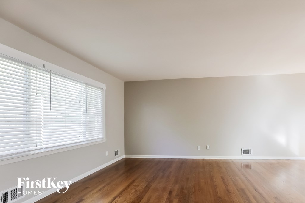 the living room of an empty house with wood floors and a large window