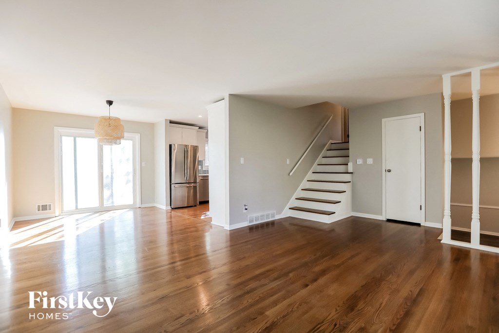 an empty living room with wood floors and a staircase