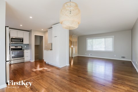 a renovated kitchen and living room with hardwood flooring and white cabinets and appliances