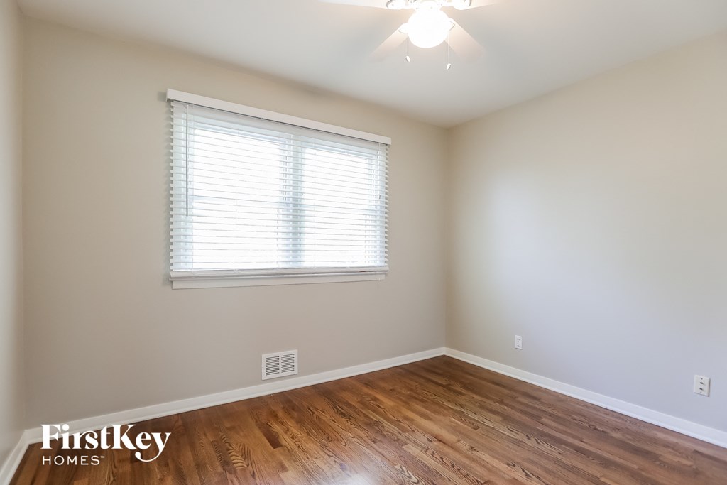 a bedroom with wood floors and a window