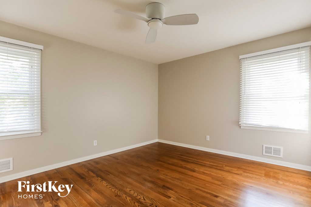 a bedroom with wood floors and a ceiling fan