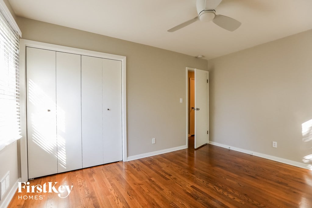 a bedroom with wood floors and a ceiling fan