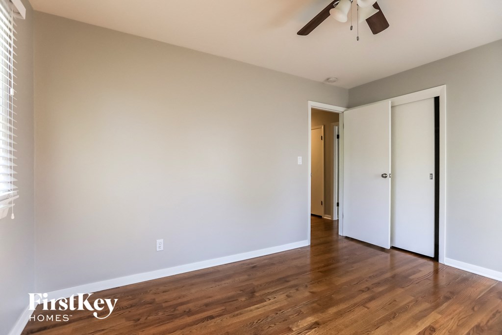 a living room with wood floors and white walls and a ceiling fan