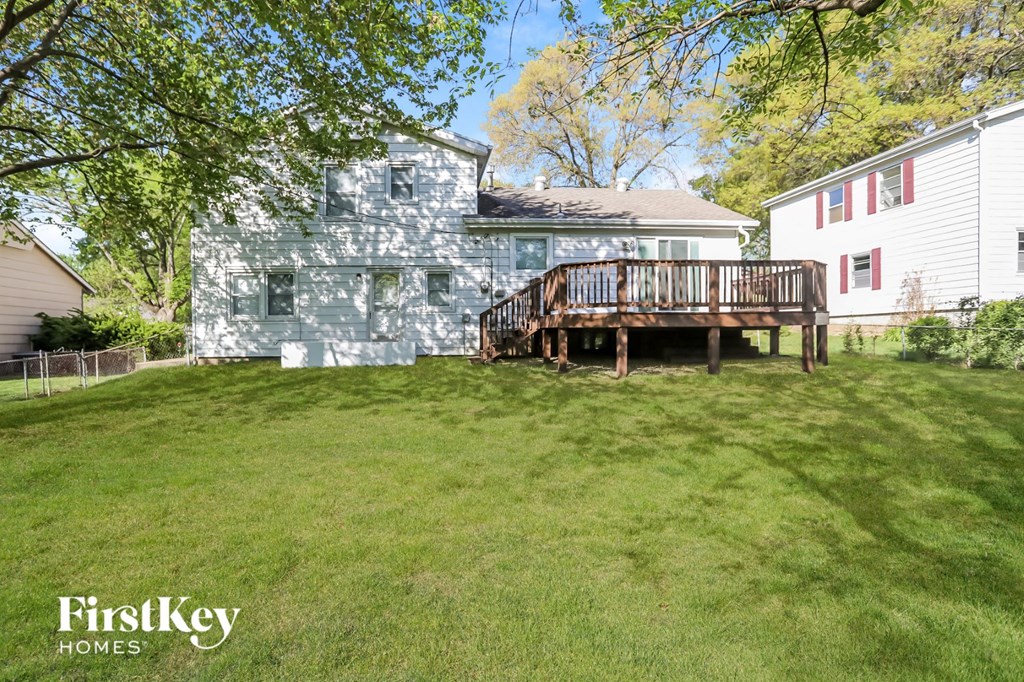 a backyard with a deck and a blue and white house