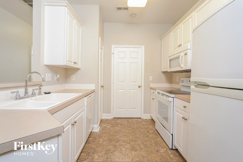 A kitchen with white cabinets and a white door.