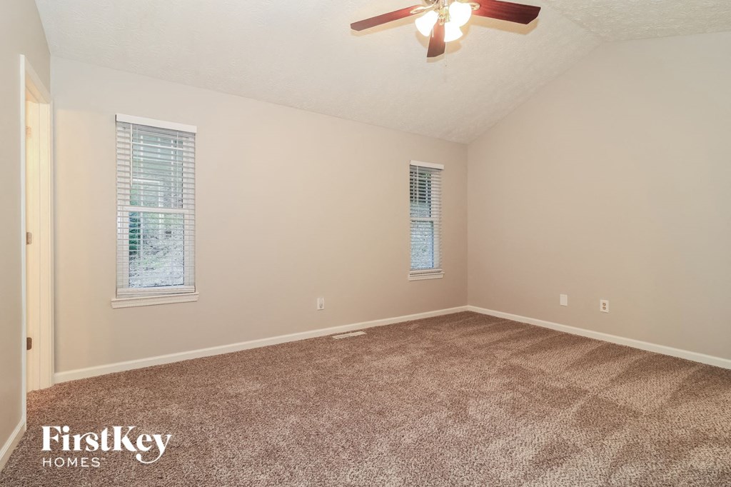 the spacious living room has carpeting and a ceiling fan