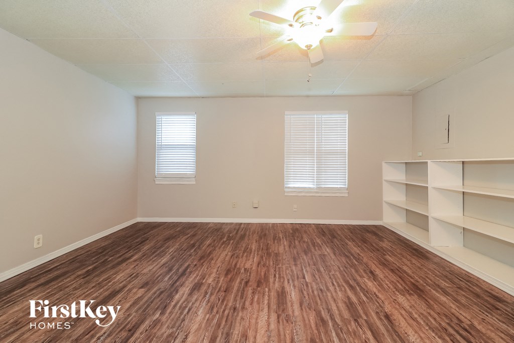 the spacious living room with wood flooring and white shelves