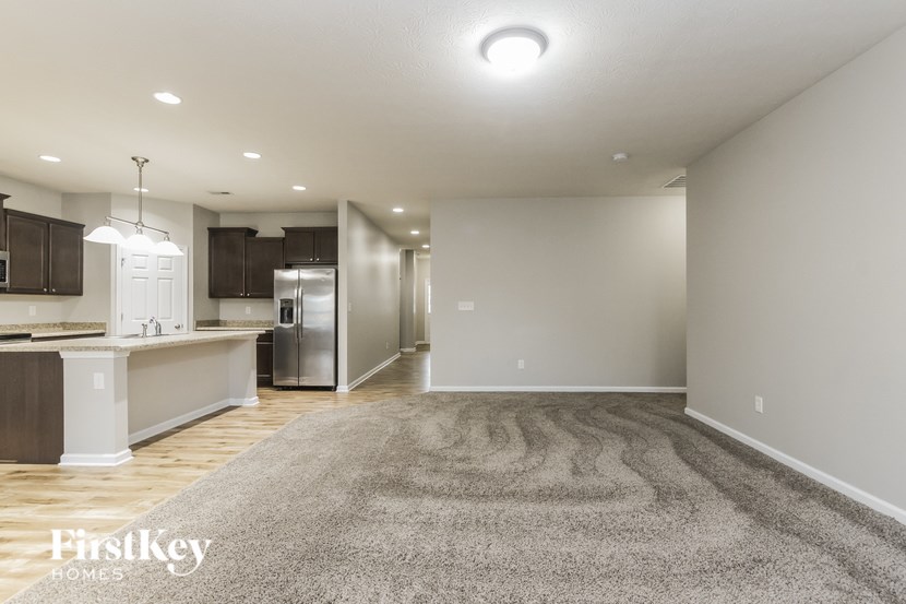 A well-lit, spacious kitchen and living area with a grey rug on the floor.