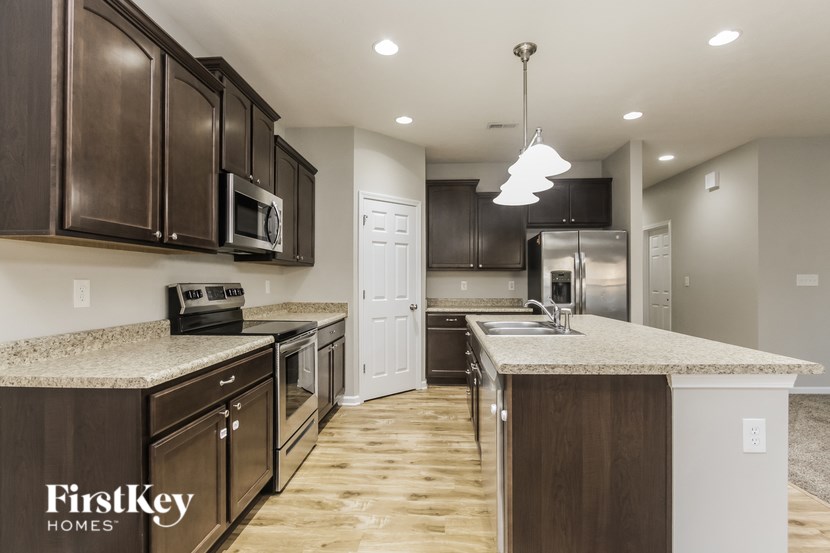 A kitchen with brown cabinets and a FirstKey Homes logo.