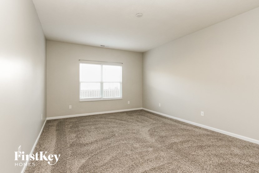 A room with a carpeted floor and a window.