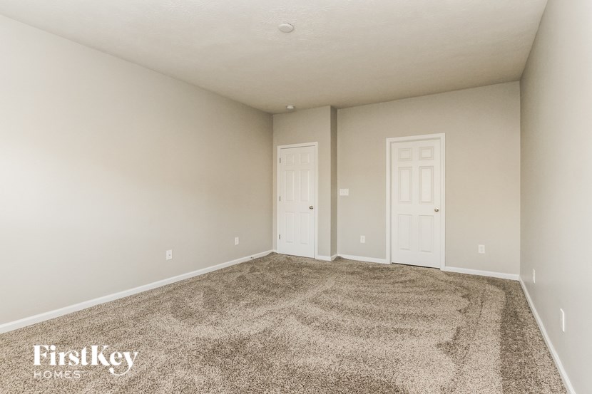 A carpeted room with two doors and a FirstKey Homes logo.