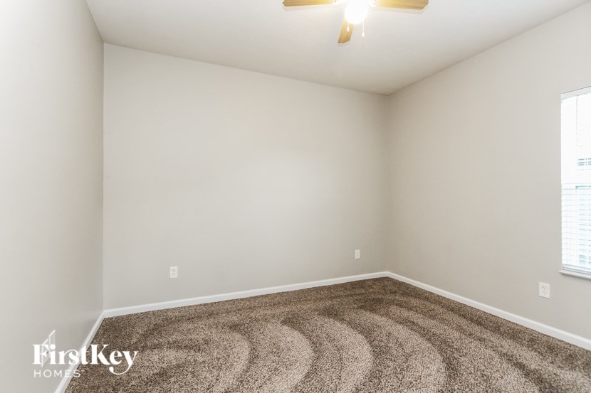 A room with a carpet floor and a ceiling fan.