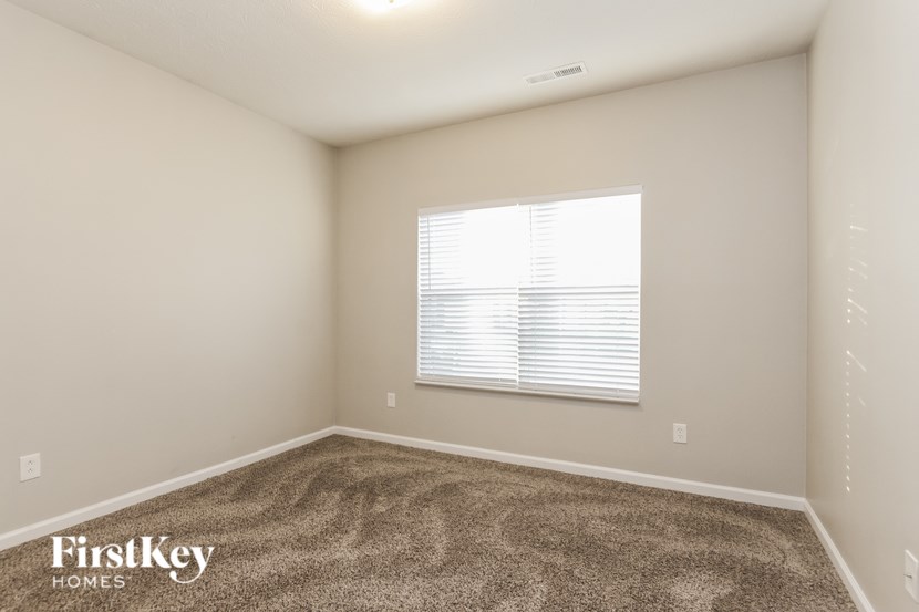 A room with a carpeted floor and a window with blinds.