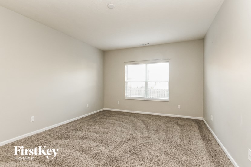 A room with a carpeted floor and a window with blinds.