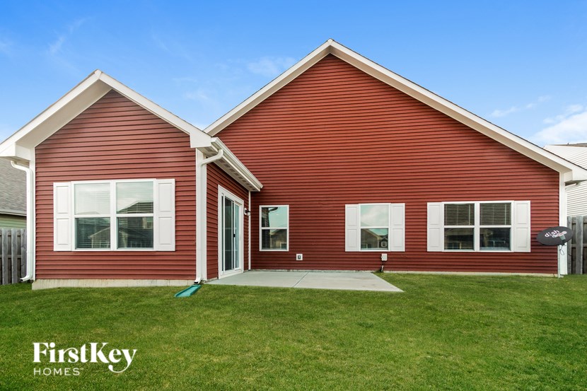 A red house with a white trim and a green lawn in front.