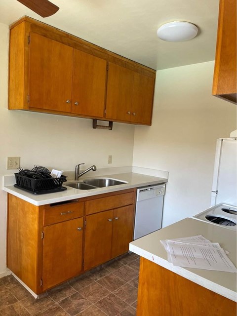 A kitchen with wooden cabinets and a white counter.