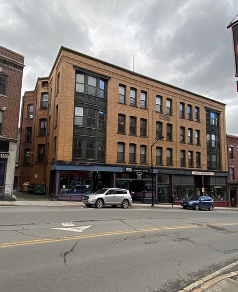 A street view of a building with cars parked in front.
