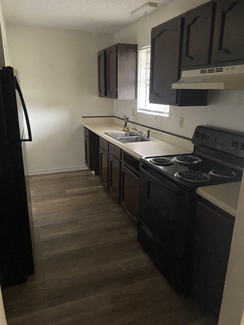 A kitchen with black appliances and brown cabinets.