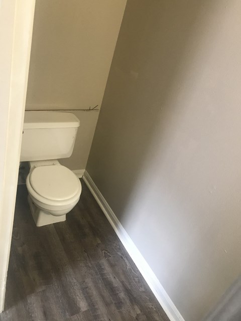 a small bathroom with a toilet and wood flooring