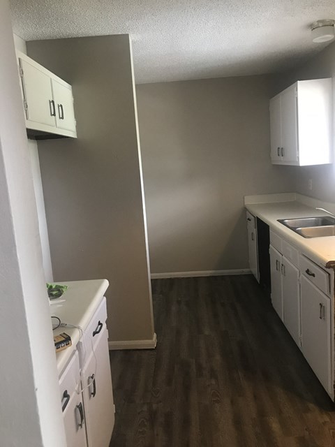 an empty kitchen with white cabinets and a sink