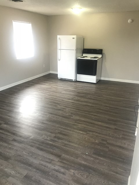 an empty living room with a refrigerator and a stove