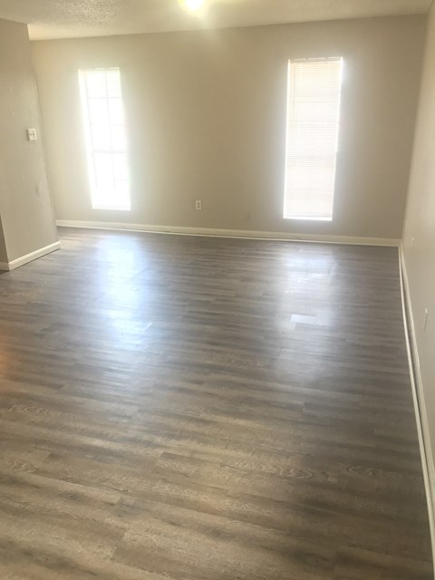 an empty living room with wood floors and white walls