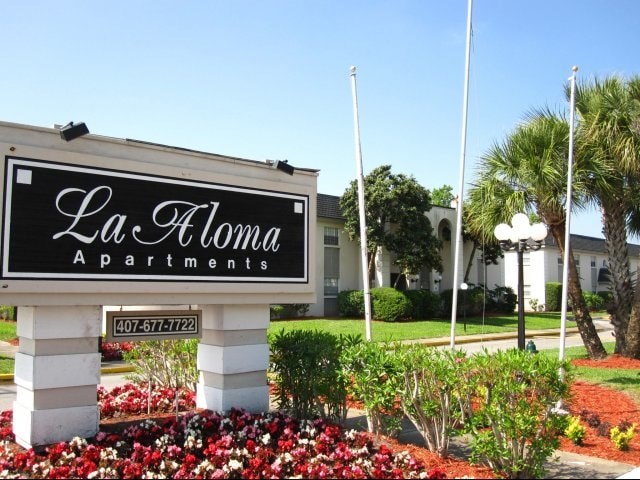 A sign for La Aloma Apartments is displayed in front of a building.