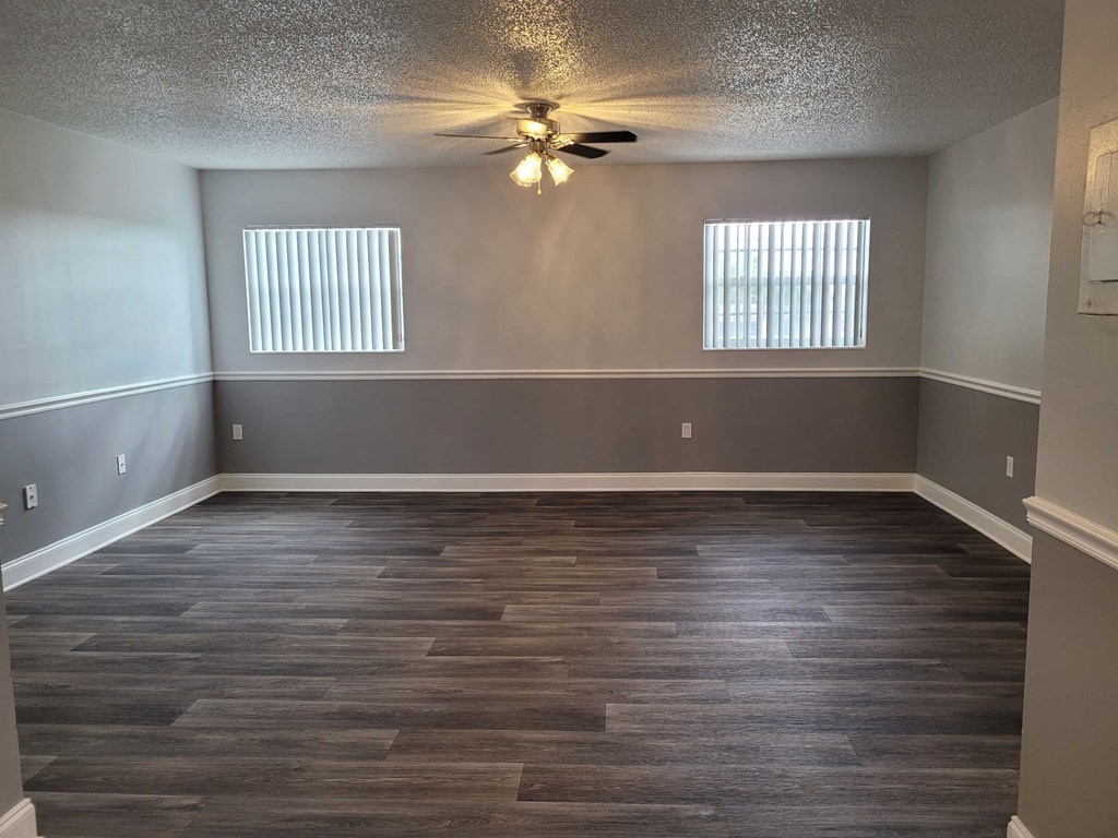A room with a ceiling fan and wood flooring.