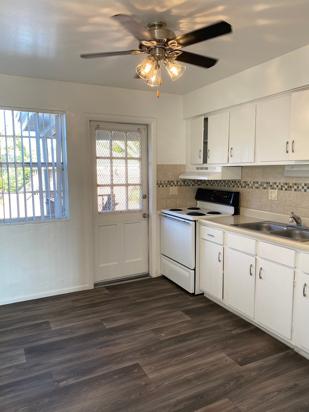 A kitchen with white cabinets and a wooden floor.