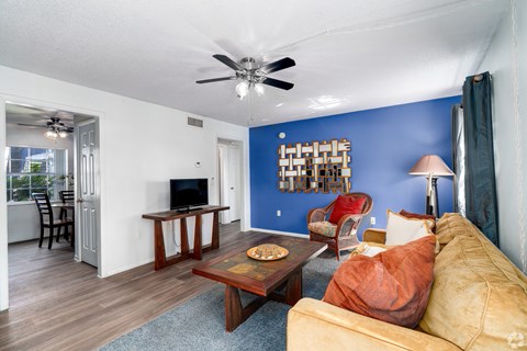 A living room with a yellow couch and a wooden coffee table.