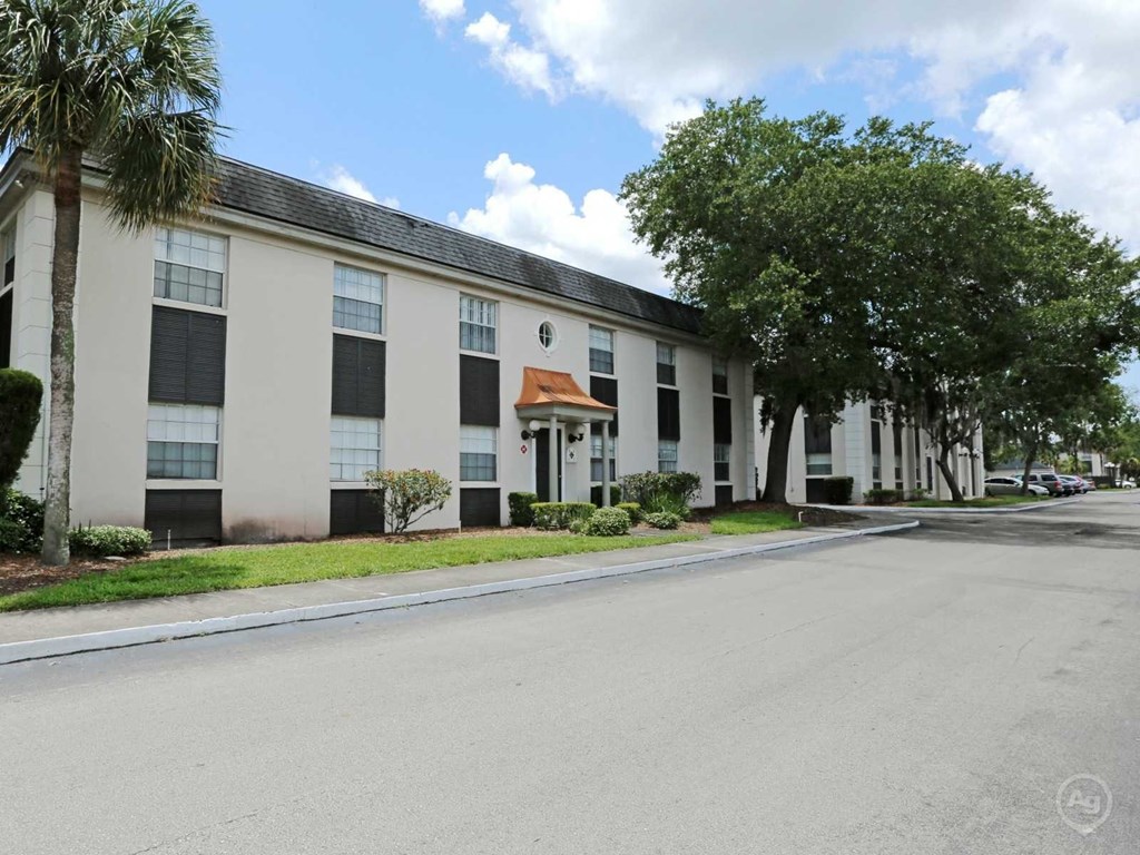 A street view of a white building with a red awning.