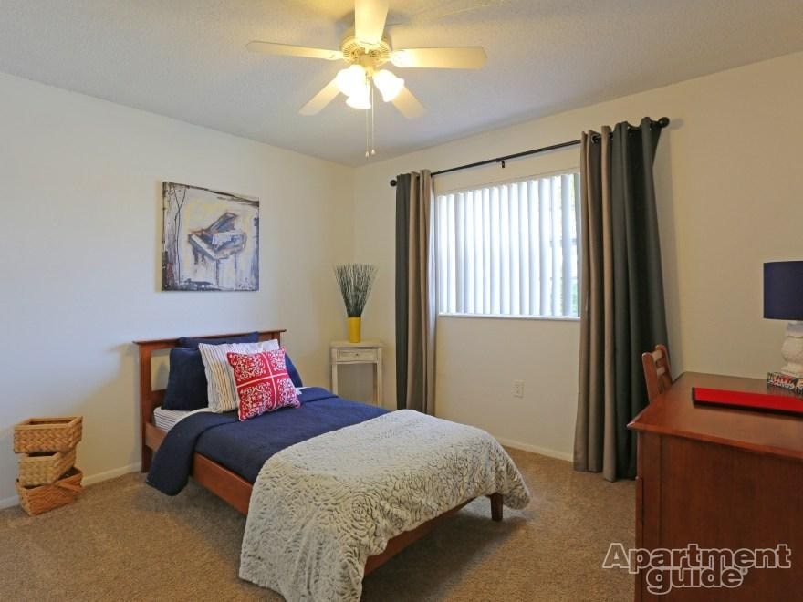 A bedroom with a bed, a ceiling fan, and a painting of a piano.