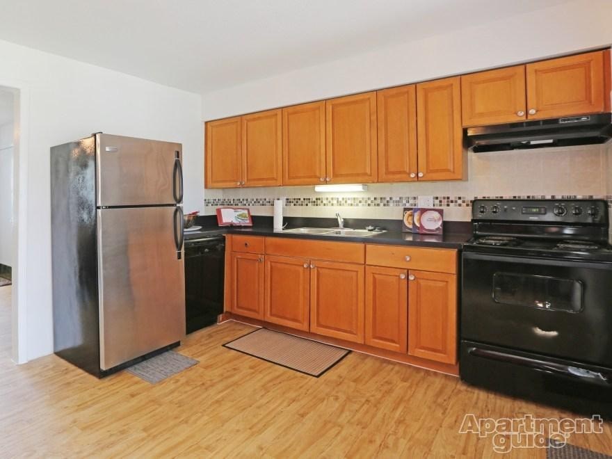 A kitchen with wooden cabinets and a stainless steel refrigerator.