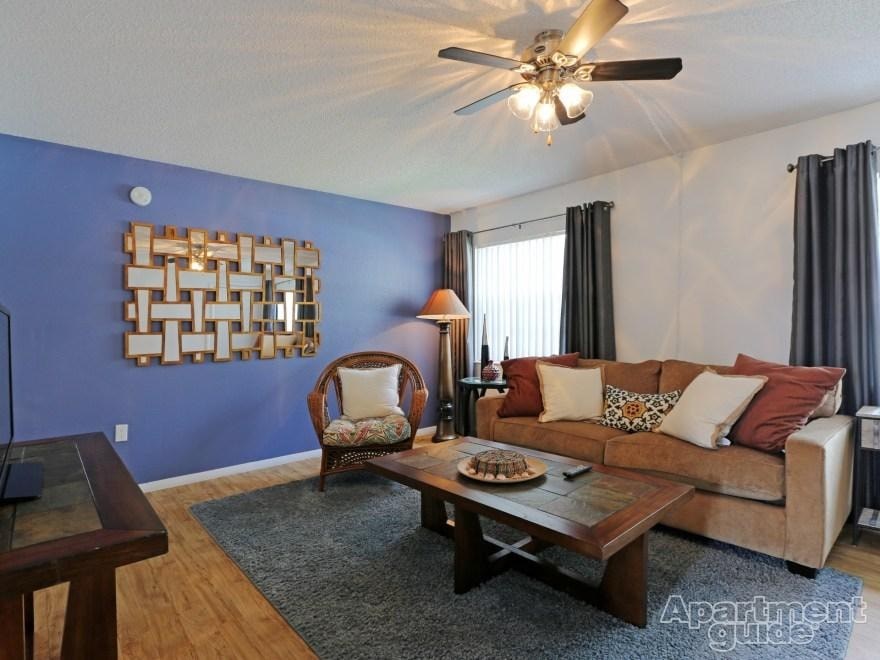 A living room with a brown couch, a wooden coffee table, and a ceiling fan.